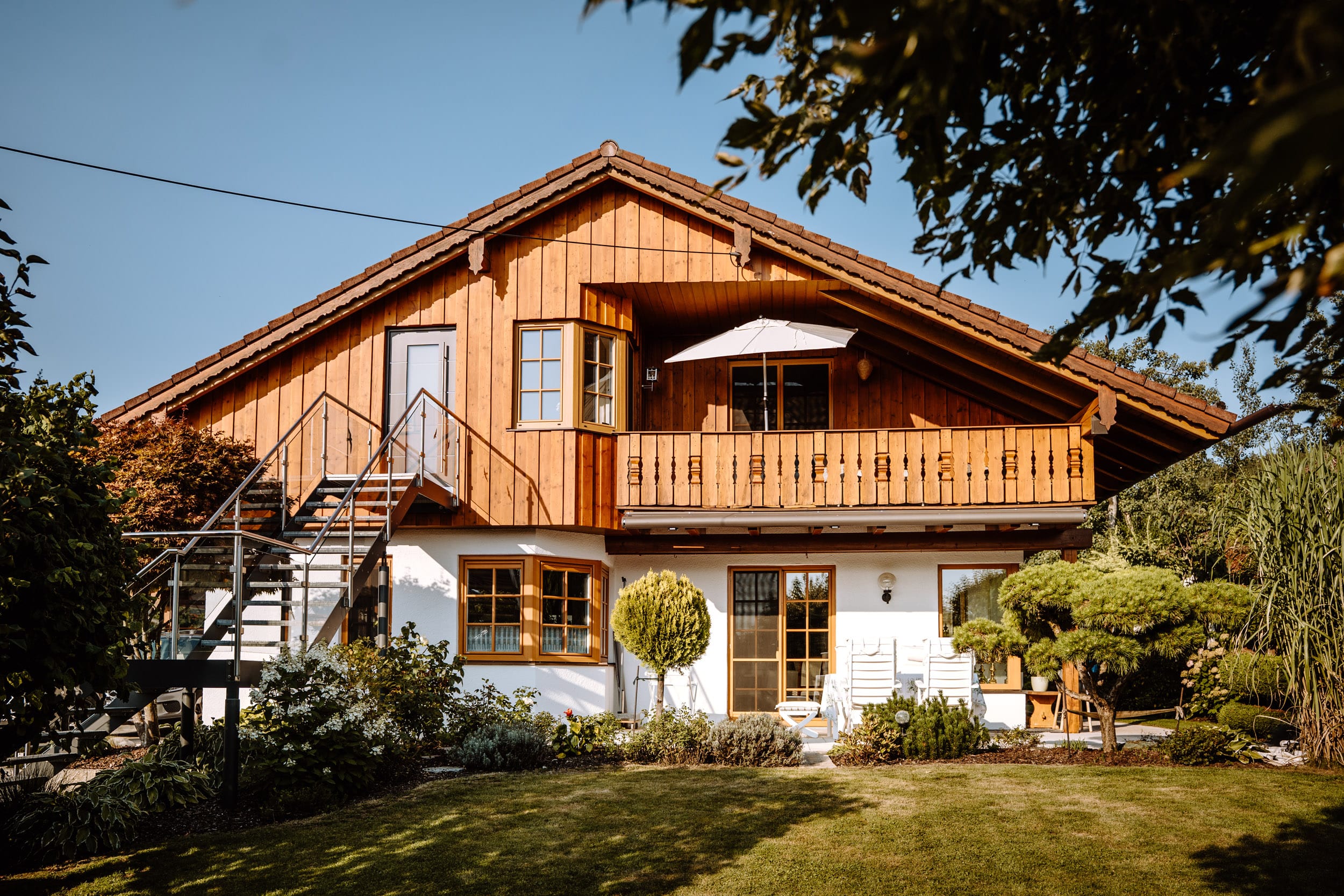 Traditionelles bayerisches Haus mit Holzfassade, Balkon und Garten