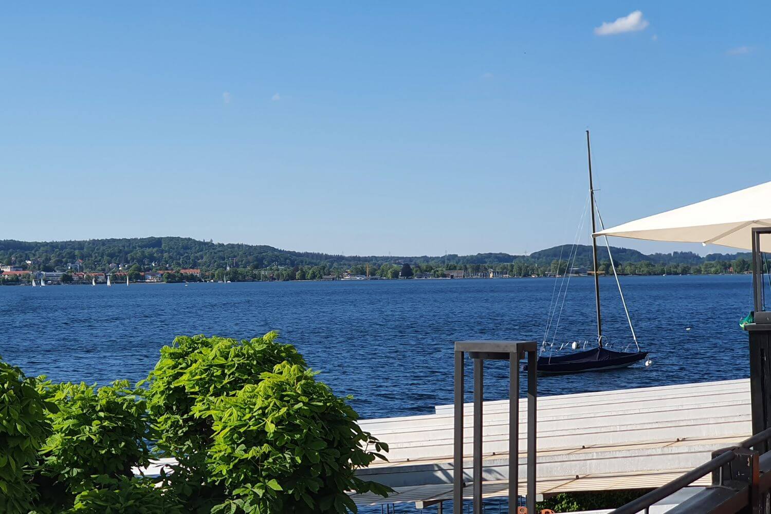 Segelboot am Steg mit Blick über den Starnberger See und Uferlandschaft